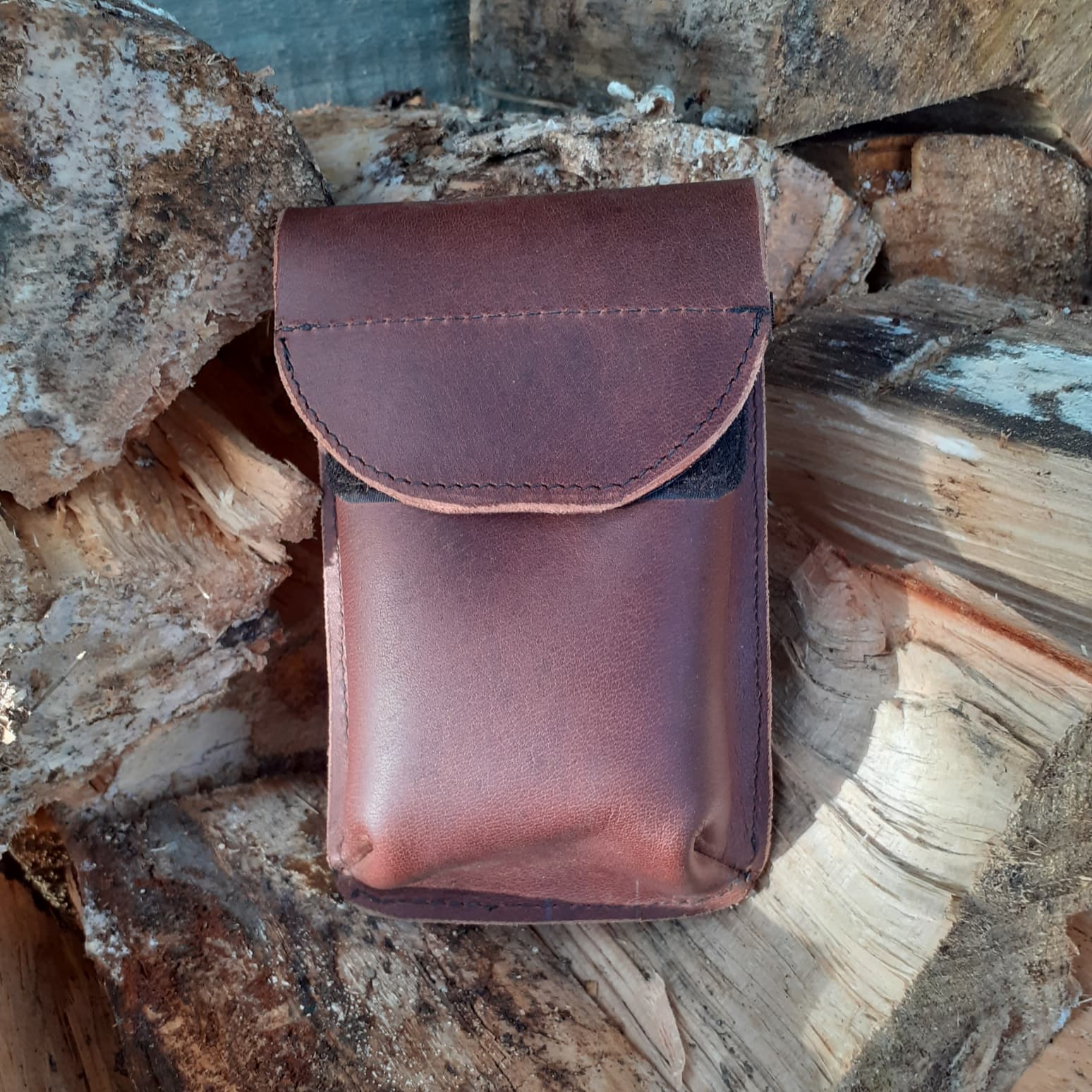 image of leather phone pouch on a firewood pile